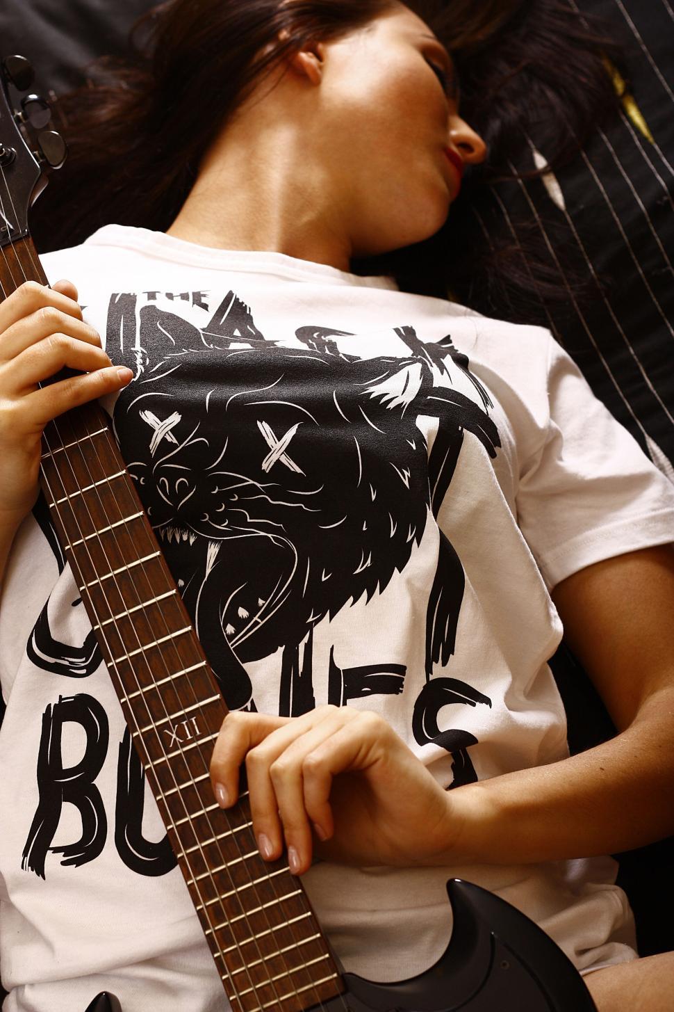 Free Image of Person holding an electric guitar wearing band artwork. 