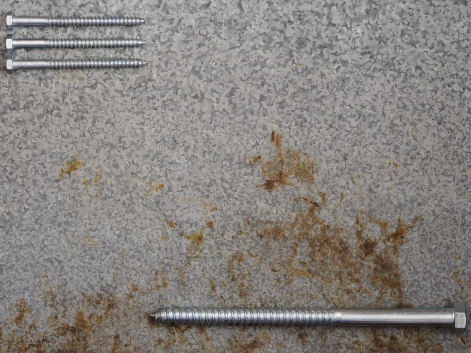 Free Image of Assorted screws on a textured metal surface 