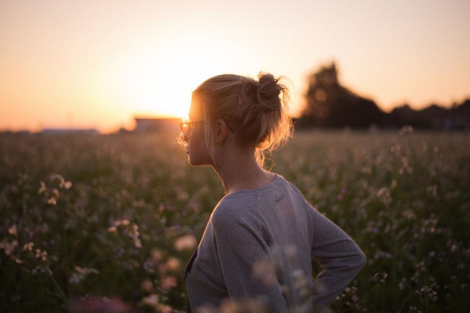 Free Image of Woman in field looking at sunset with serene expression 