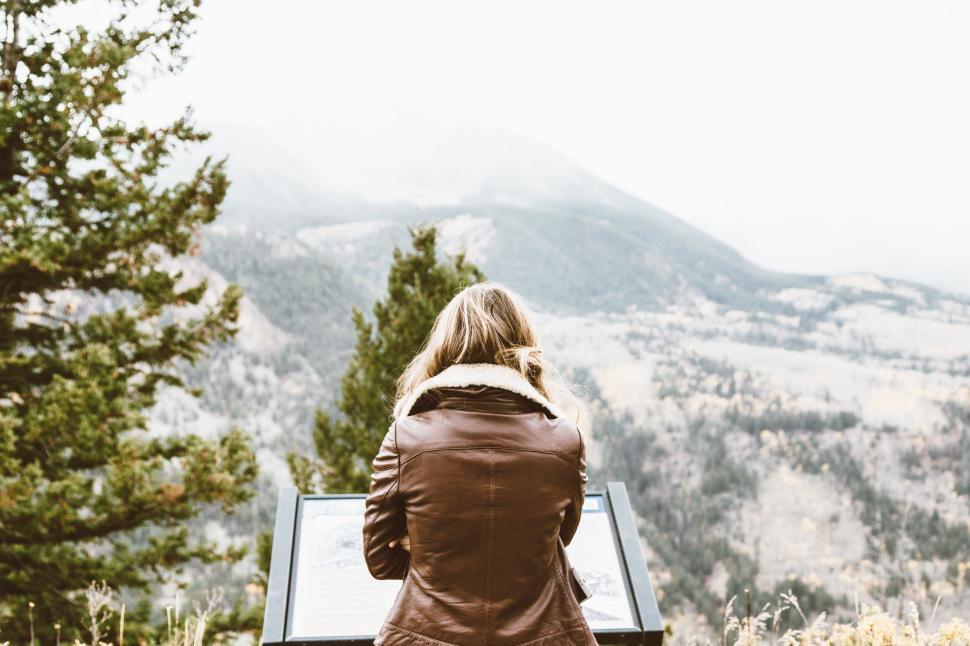 Free Image of Person reading plaque in mountains with winter coat 