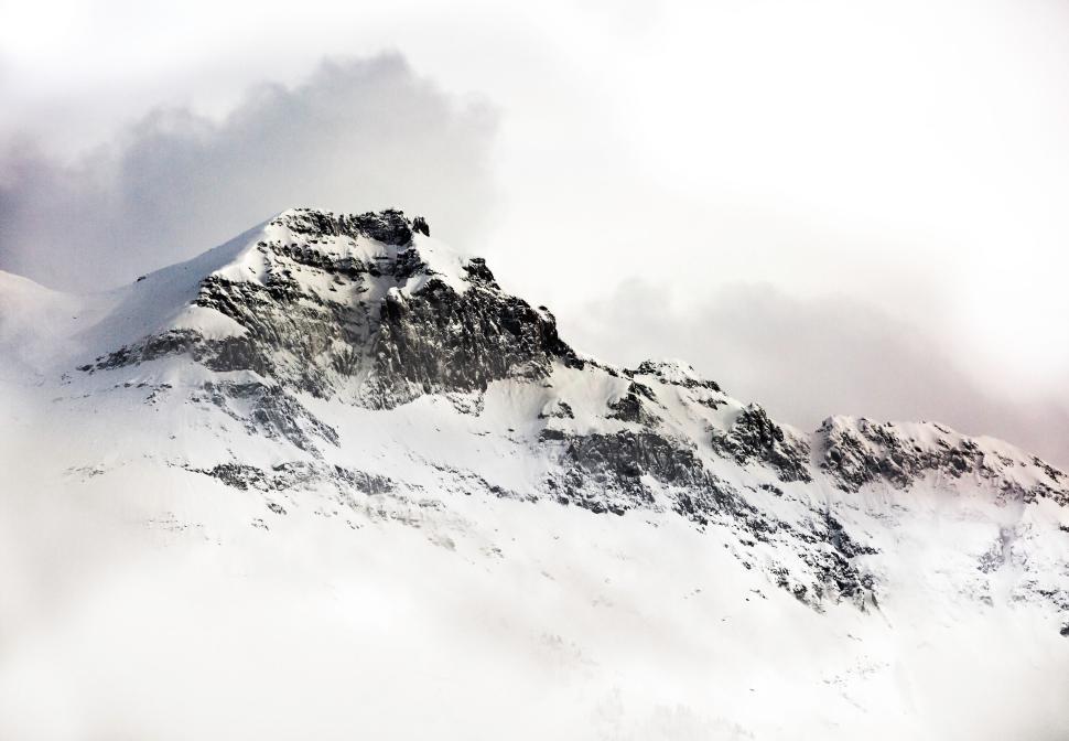 Free Image of Snow-covered mountain peak with rugged ridges visible. 