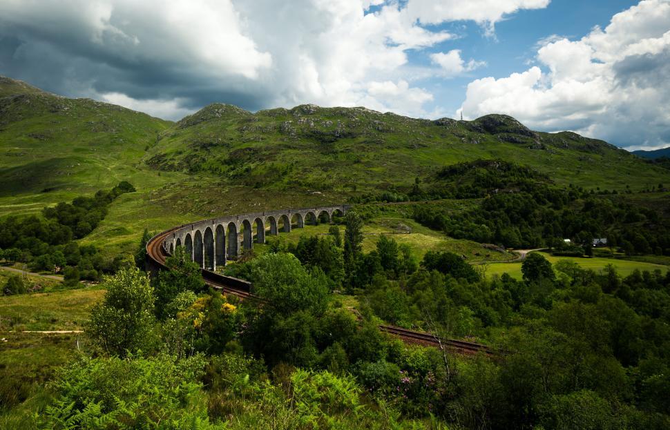 Free Image of Iconic viaduct crossing lush green rolling hills 