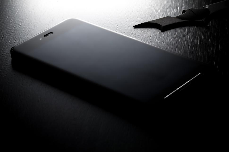 Free Image of Close-up of a smartphone on a dark surface with light. 