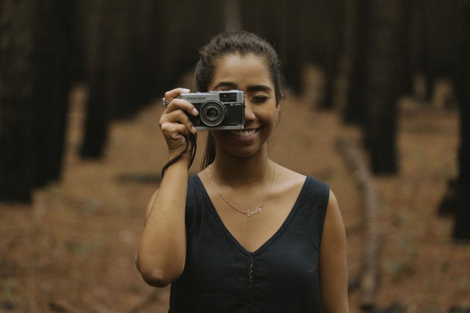 Free Image of Person holding a camera against blurred forest background 