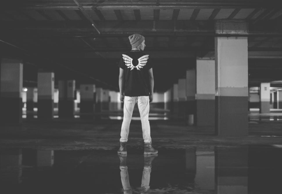 Free Image of Person stands in an empty parking garage, wings on shirt 