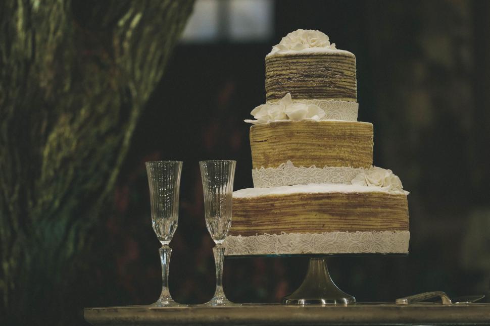 Free Image of Elegant multi-tiered cake displayed with two glasses. 