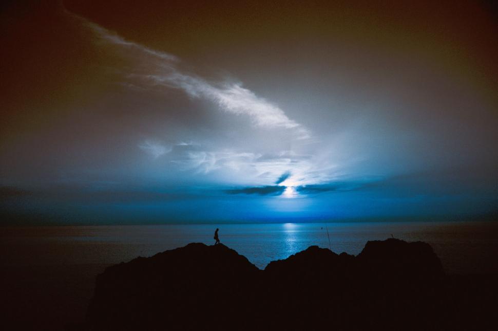 Free Image of Person silhouetted against a stunning ocean sunset. 