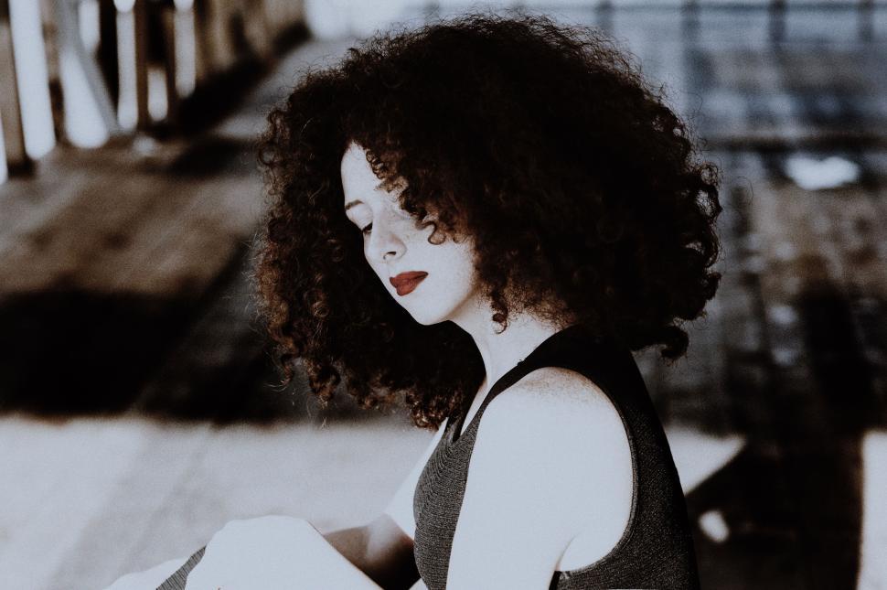 Free Image of Woman seated with curly hair in a rustic setting. 