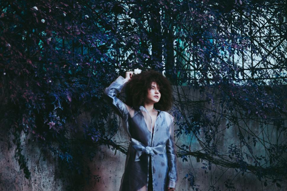 Free Image of Woman with flowers in her hair in a blue-tinted scene. 