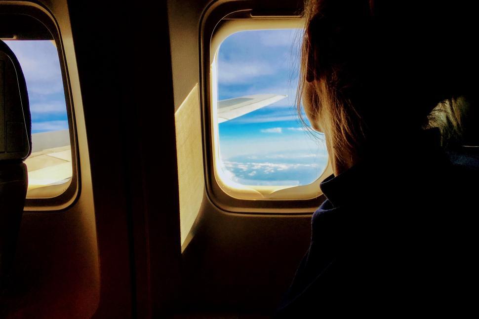 Free Image of Silhouette in airplane with wing outside the window view 