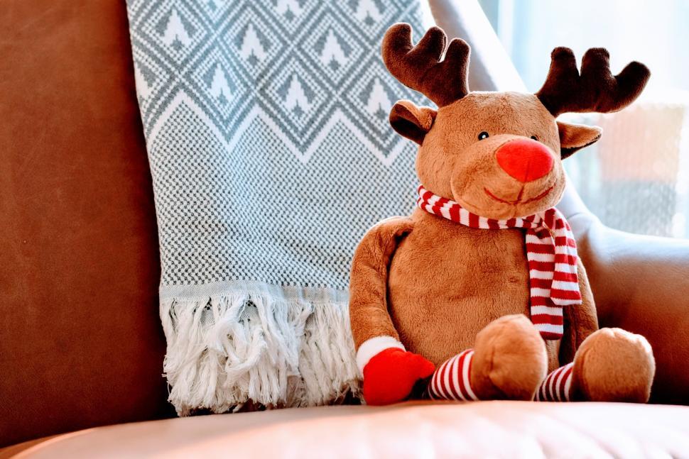 Free Image of Plush reindeer toy sitting on a cozy armchair in light. 