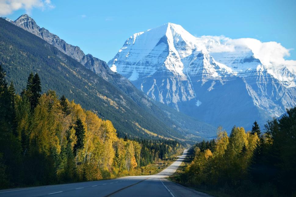 Free Image of Sunny mountain road leading to a majestic snow peak. 