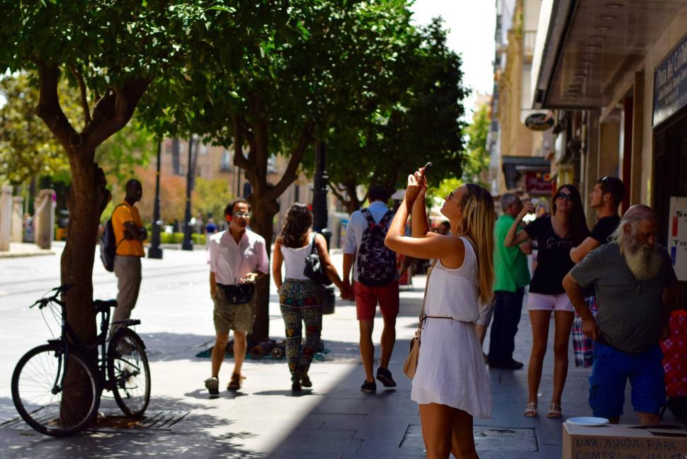 Free Image of People on street with shops, trees and casual atmosphere. 