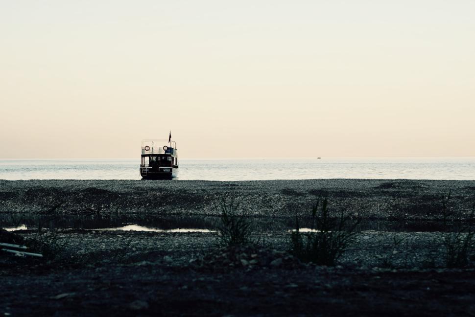 Free Image of Lonely boat sits on the shore against the calm sea. 