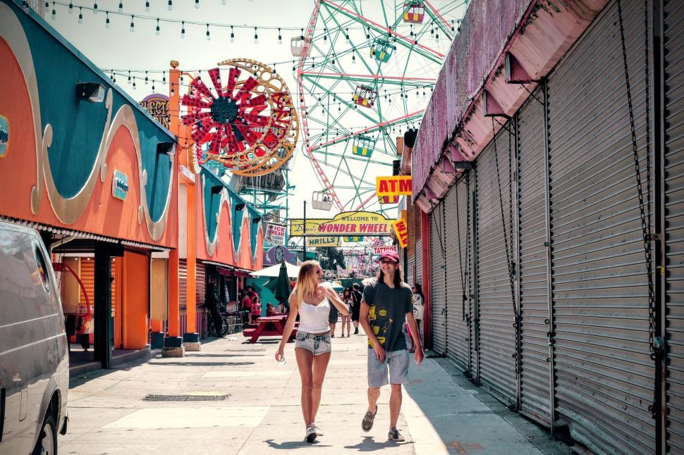 Free Image of Couple walking through amusement park with ferris wheel. 