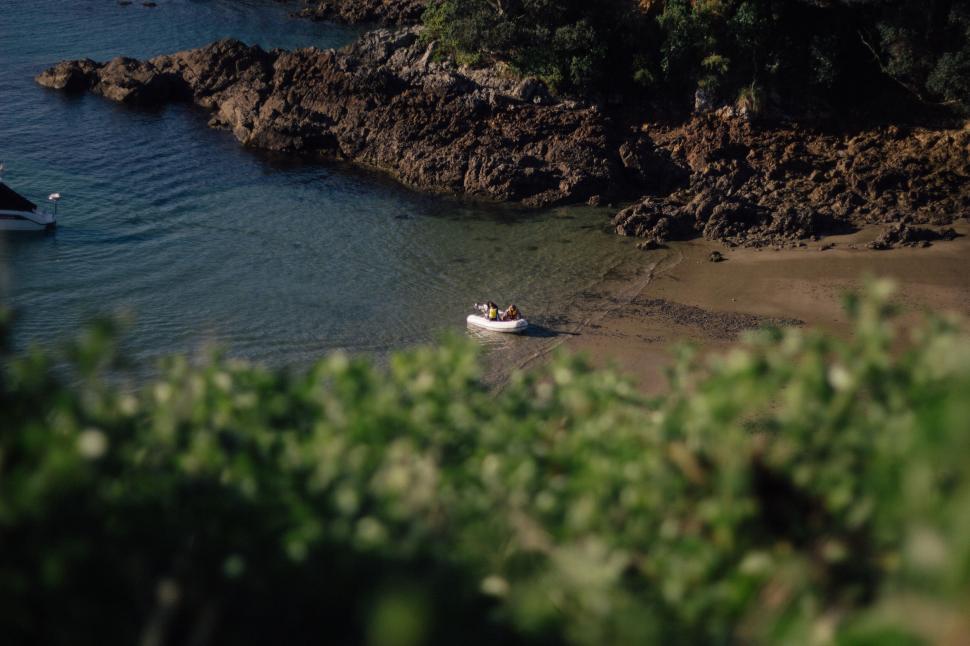 Free Image of White boat by the rugged beach and clear water. 