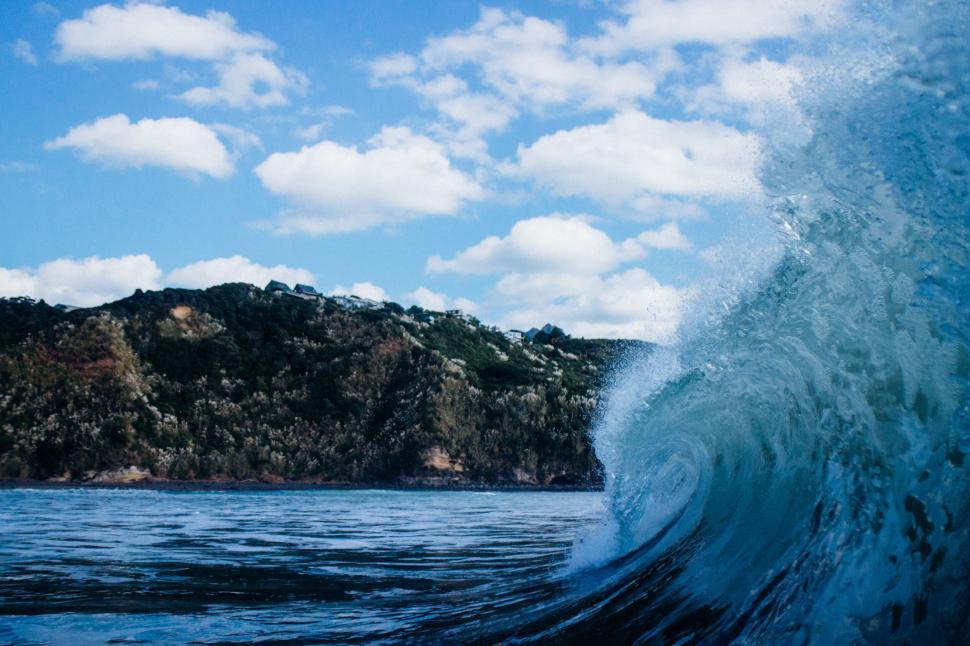 Free Image of Powerful ocean wave with rocky coastline backdrop 