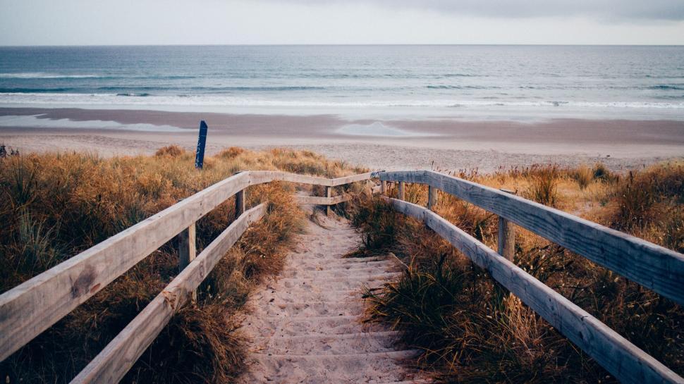 Free Image of Wooden pathway leading to a serene ocean shore 