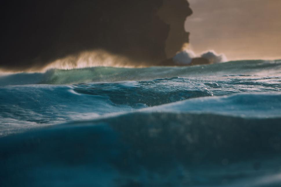 Free Image of Ocean waves crashing against rugged cliffs at dawn 