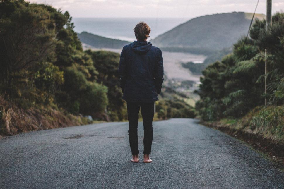 Free Image of Person walking barefoot on road leading to scenic viewpoint. 