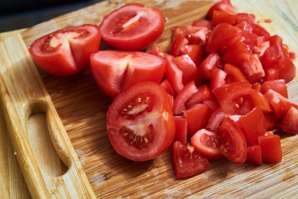 Free Image of Wooden cutting board with chopped and halved tomatoes 
