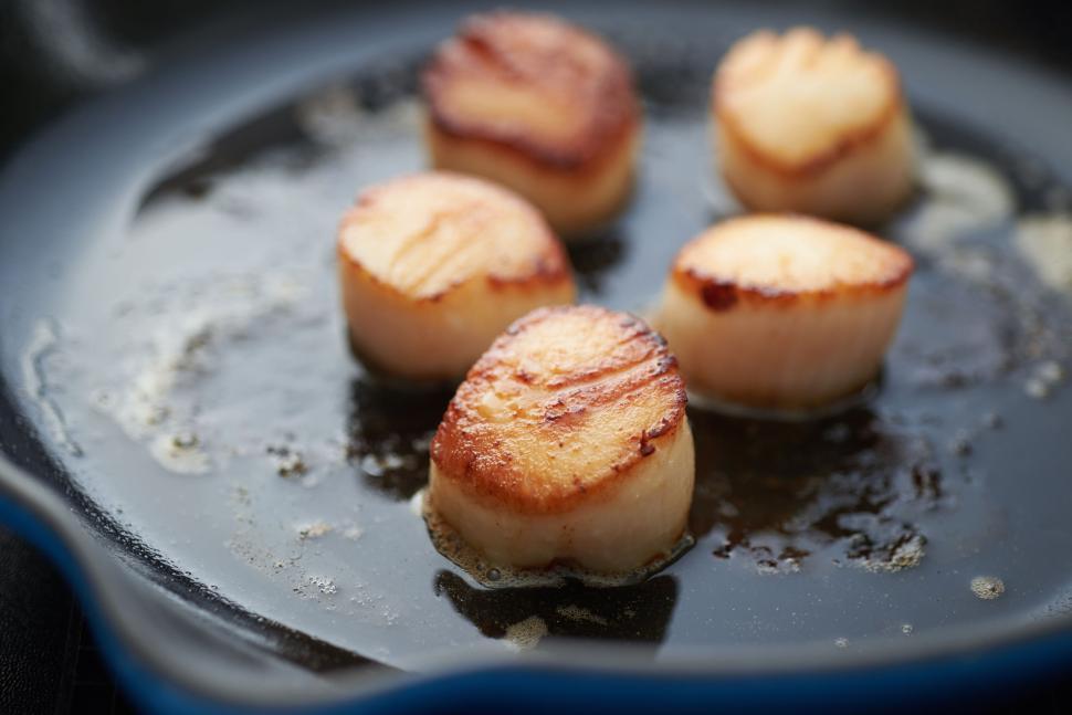 Free Image of Seared scallops cooking in a hot frying pan with butter 