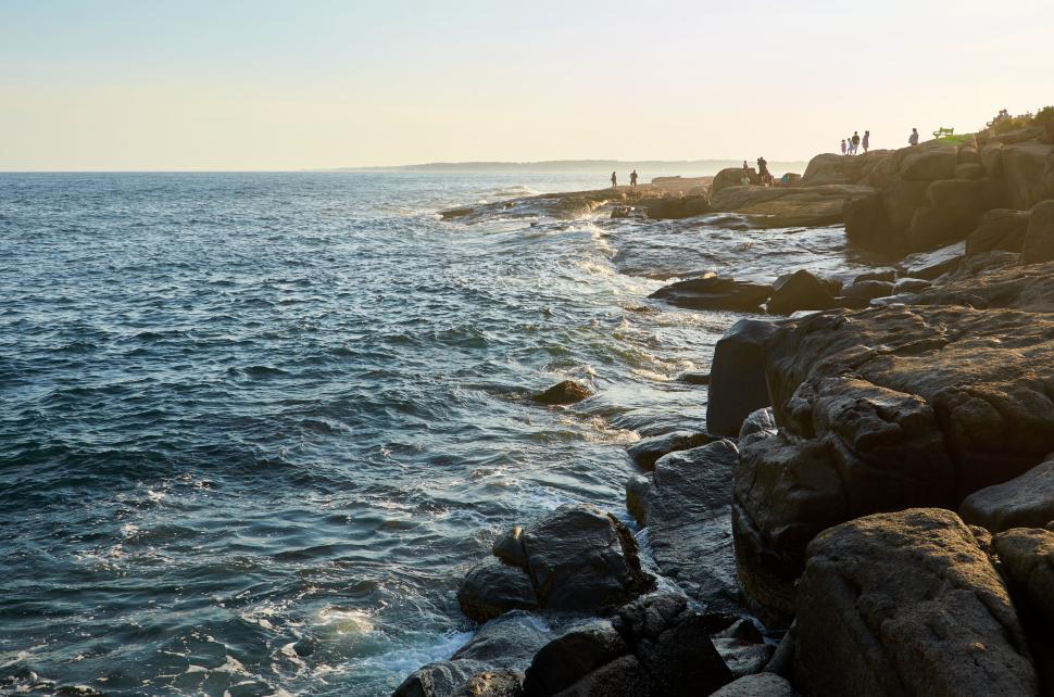 Free Image of People fishing on rocks by the sea during sunset. 