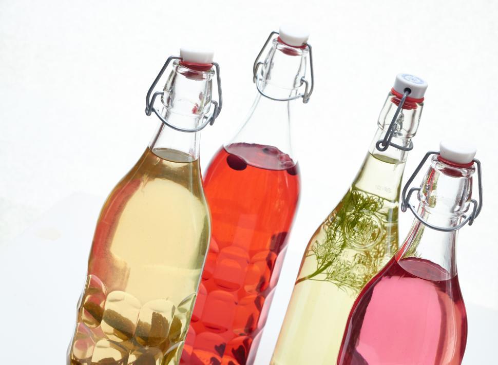 Free Image of Four glass bottles of colored beverages with stopper caps 