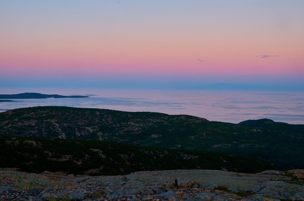 Free Image of Beautiful pink and blue sky over rolling green hills 