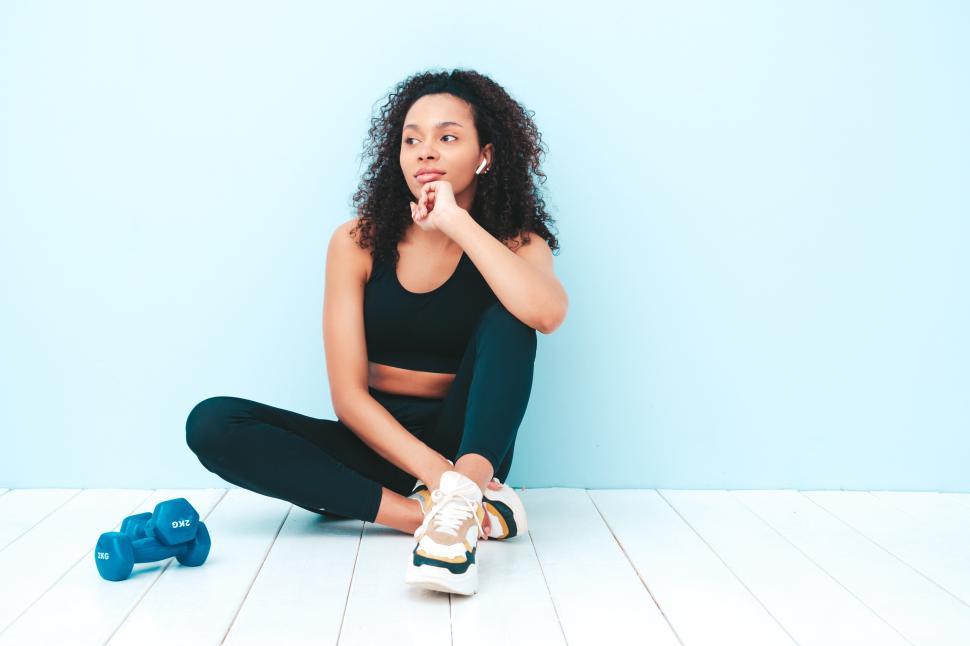 Free Image of Pensive woman in active wear beside blue dumbbells 
