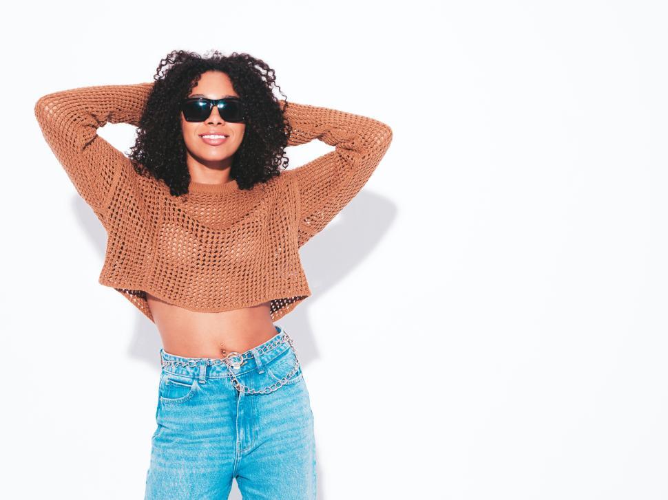 Free Image of Woman in brown sweater and jeans posing casually 