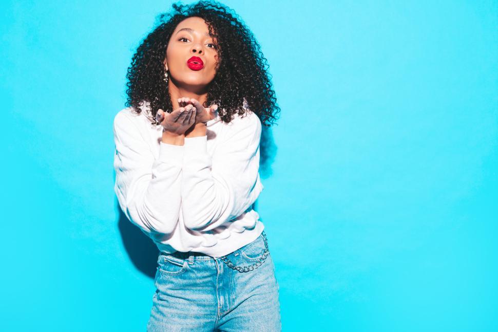 Free Image of Woman in white hoodie blowing a kiss playful stance 