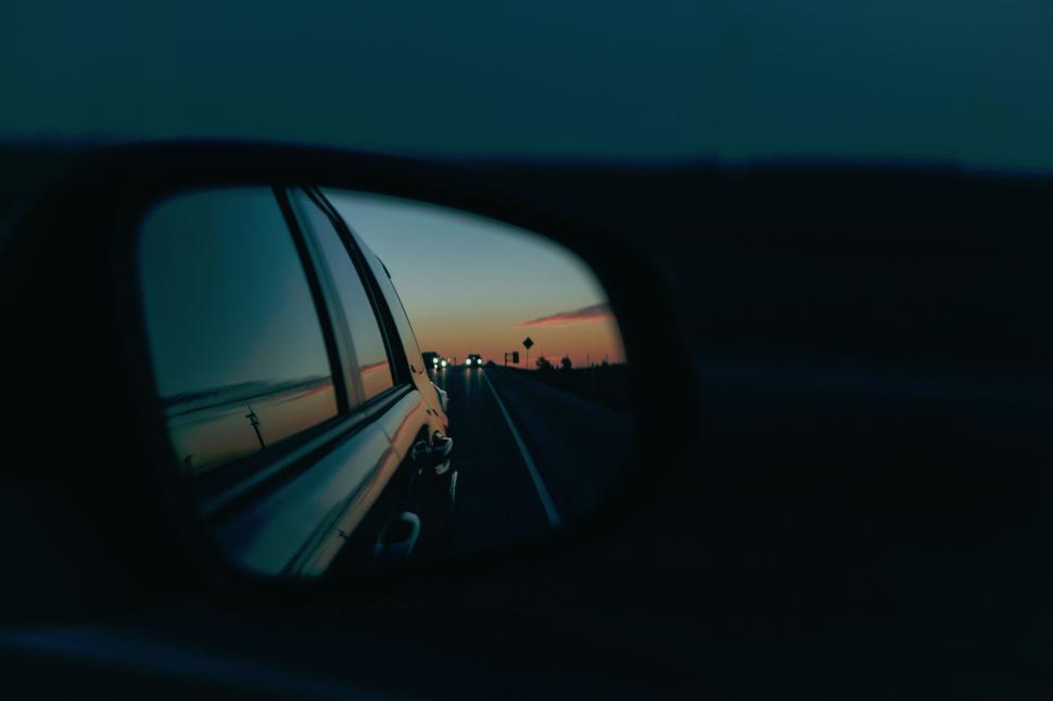 Free Image of Rearview mirror reflecting sunset on busy highway. 