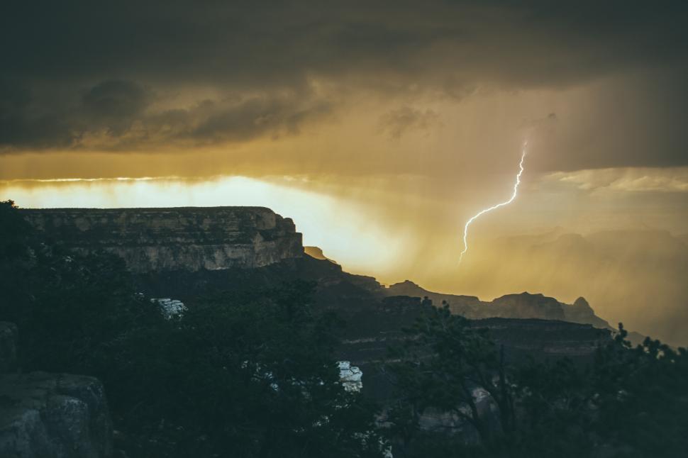 Free Image of Lightning bolt strikes through moody stormy canyon evening 