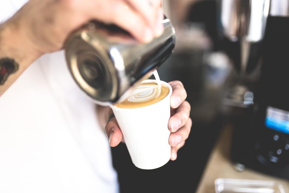 Free Image of Close-up of barista pouring latte art into a cup. 