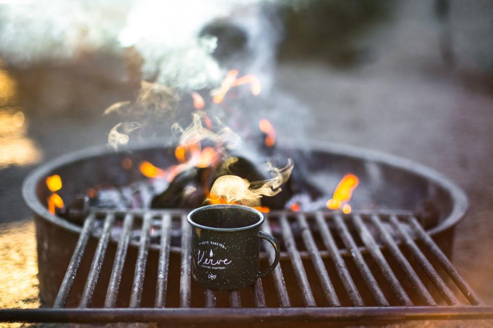 Free Image of Coffee Mug Steaming on a Campfire Grill 