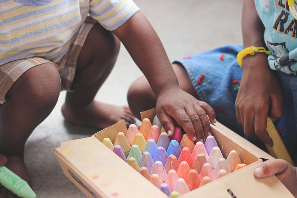 Free Image of Children s hands picking colorful chalk from box set. 