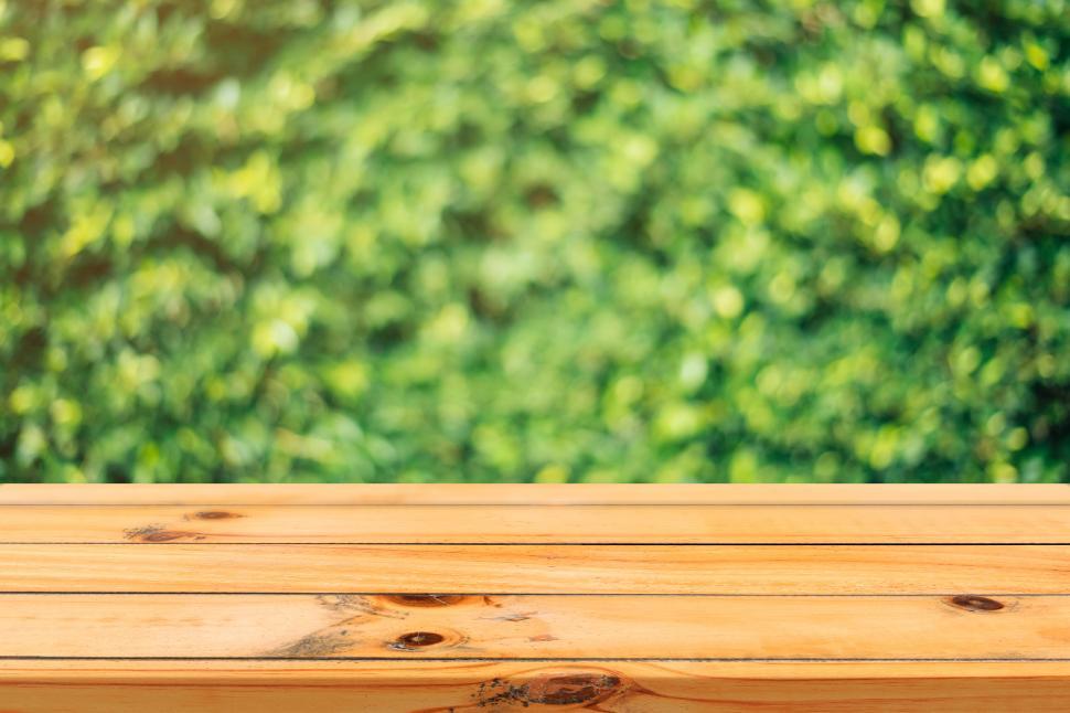Free Image of Wooden table with a blurred natural greenery backdrop. 