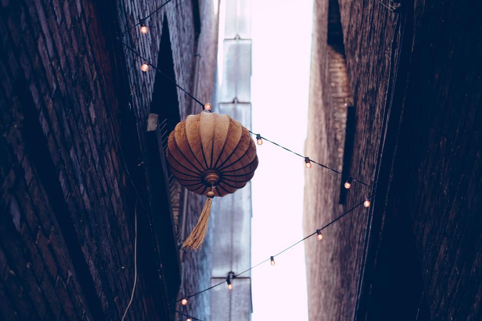 Free Image of A lantern hanging between two brick buildings, twilight 