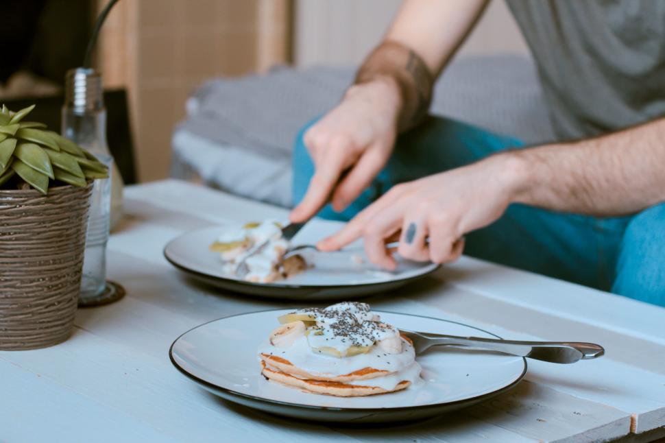 Free Image of Person enjoying pancakes with cream and fruits on plates 