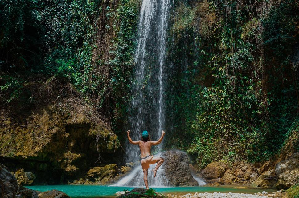 Free Image of Person enjoying nature in swimwear under a waterfall outdoors 