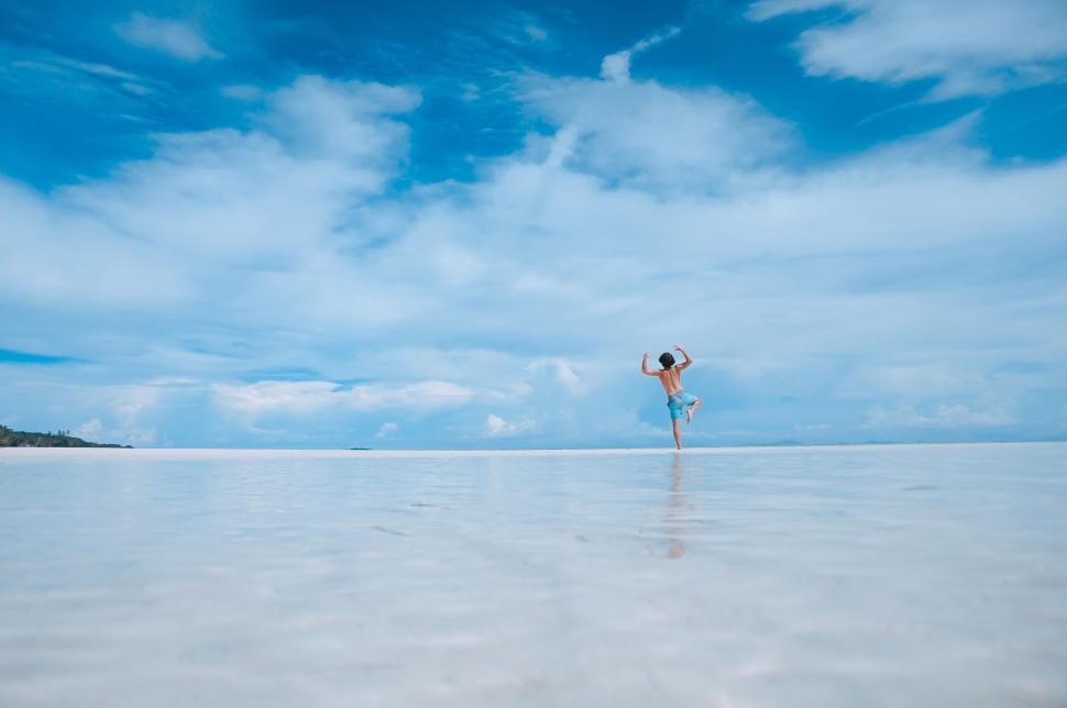 Free Image of Person joyfully jumping in the shallow ocean water 