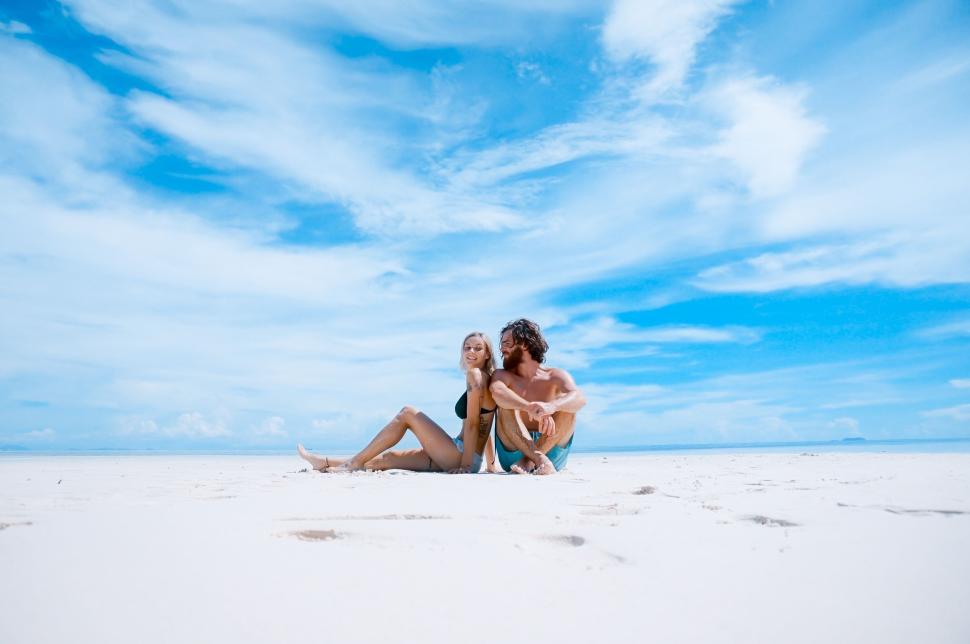Free Image of Couple embracing on a sunlit beach with clear sky. 