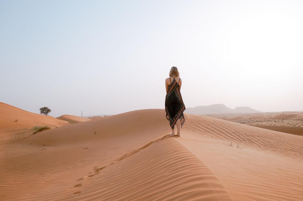 Free Image of Person walking alone in vast desert dunes with sunrise 