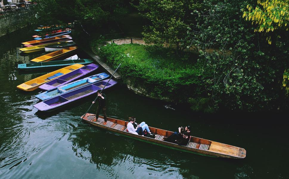 Free Image of Two people enjoying punting on a peaceful, scenic river 