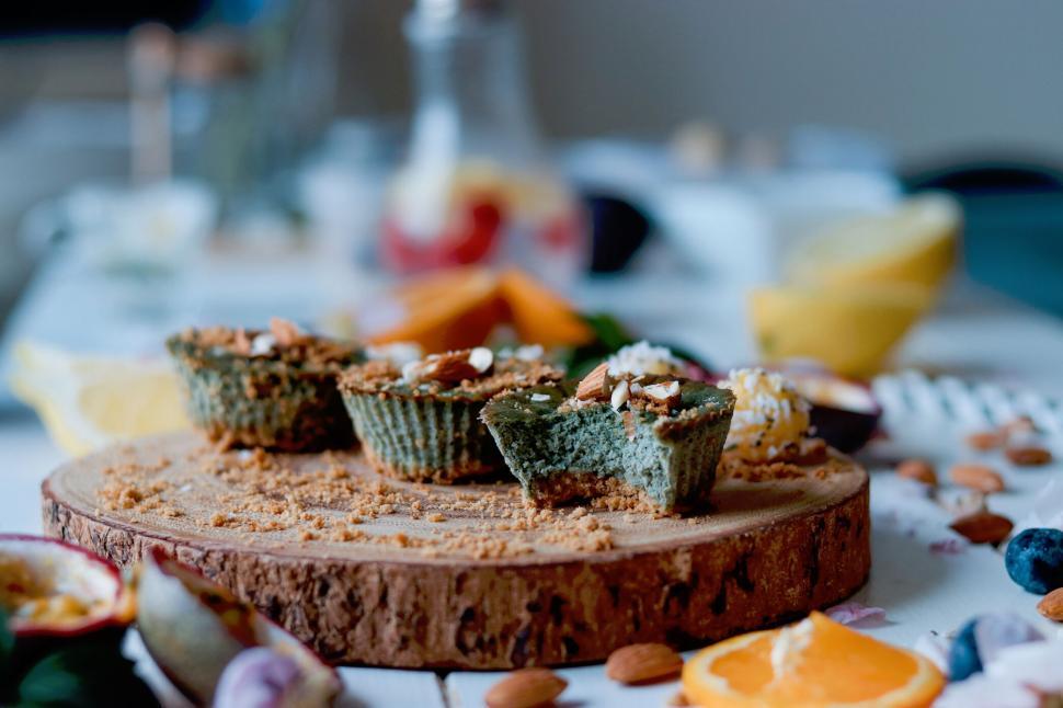 Free Image of A wooden board with three muffins and scattered nuts 