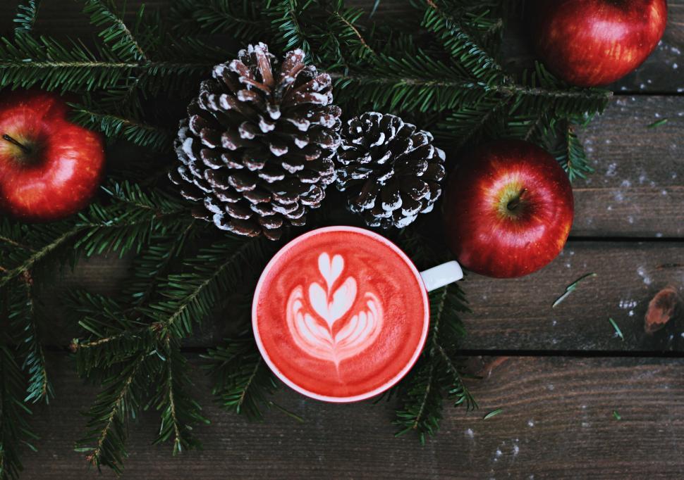 Free Image of Red foamy decorative drink surrounded by pinecones and apples 