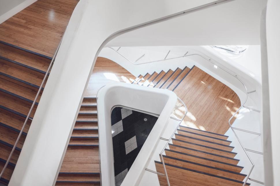 Free Image of Spiraling staircase with wooden steps and light rail. 