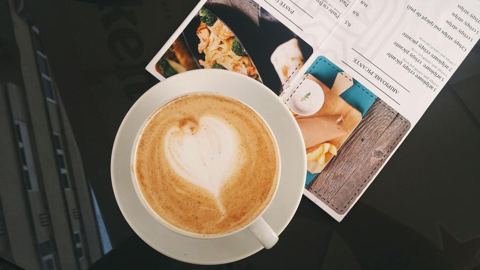 Free Image of Heart-shaped latte art on coffee cup beside menu 