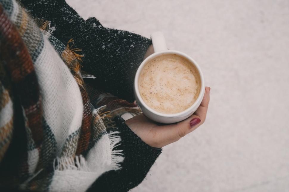 Free Image of Warming coffee cup held by person in a cozy scarf 